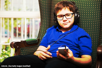 tween in an armchair, at home, listening to a podcast