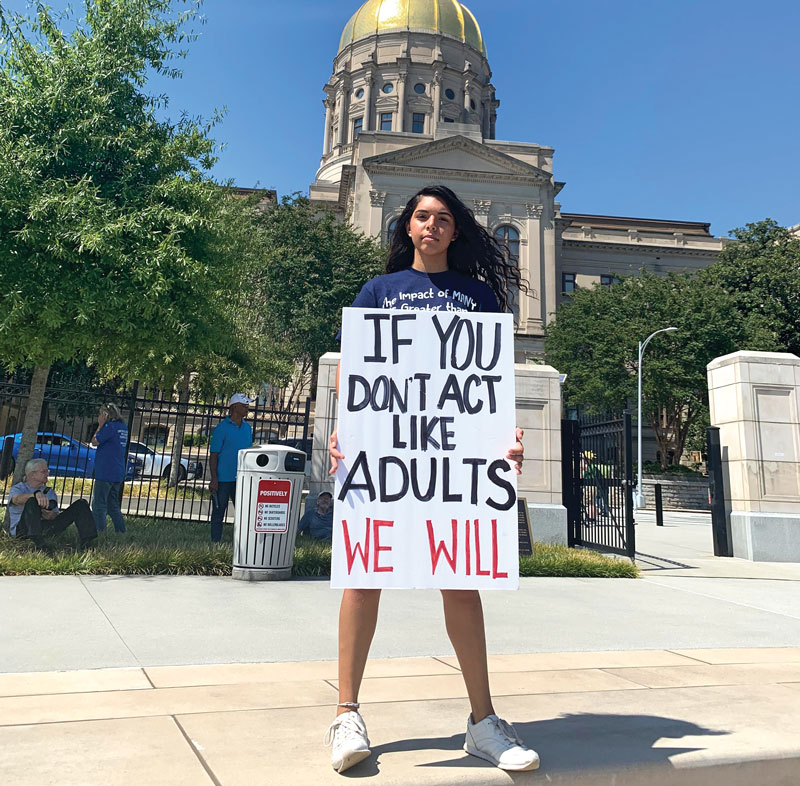 Hannah Testa believes encouraging teens to talk solutions is key to the environmental justice movement. Teen holding sign