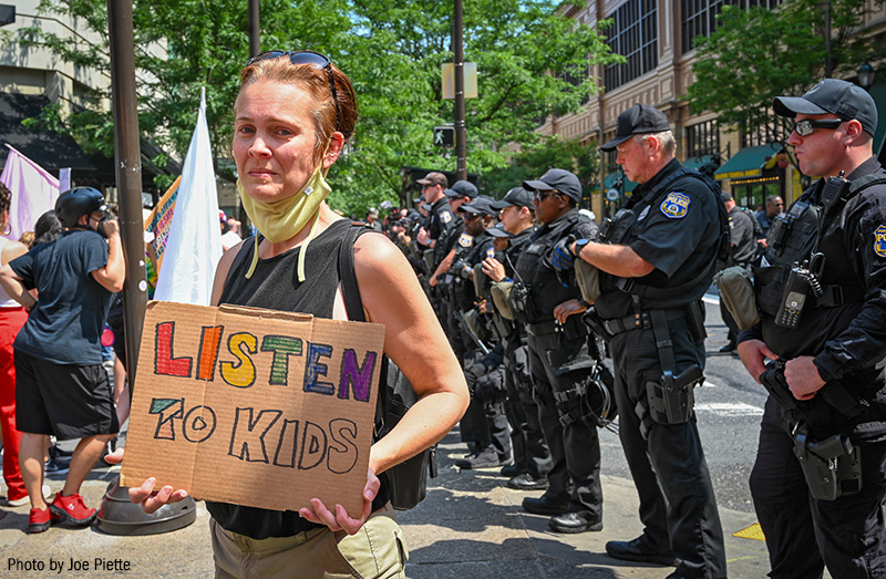 Protester at a Moms for Liberty event, holding a sign that reads